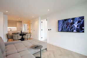 A modern living room with a sofa, a dining area with chairs and a table, and a large abstract painting on the wall. - Urbano | The Heim (Greater Manchester)