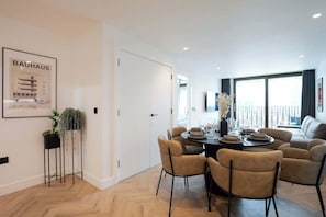 A modern dining area with a round table, four chairs, and a view of the outdoors.