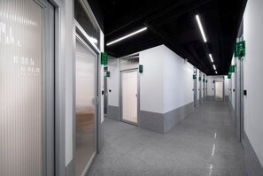 A clean, modern hallway with doors marked by green signs, leading to individual rooms. - WeFlow Youth Hostel - Shanghai People's Square Jing'an Joy City (Shanghai)