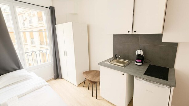 A compact kitchen with a sink, a coffee machine, and a compact dishwasher.