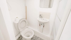 A small, white bathroom with a toilet, a sink, and a mirror.
