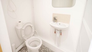 A bathroom with a toilet, sink, and shower.