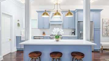 A kitchen with a central island, bar stools, and a chandelier.