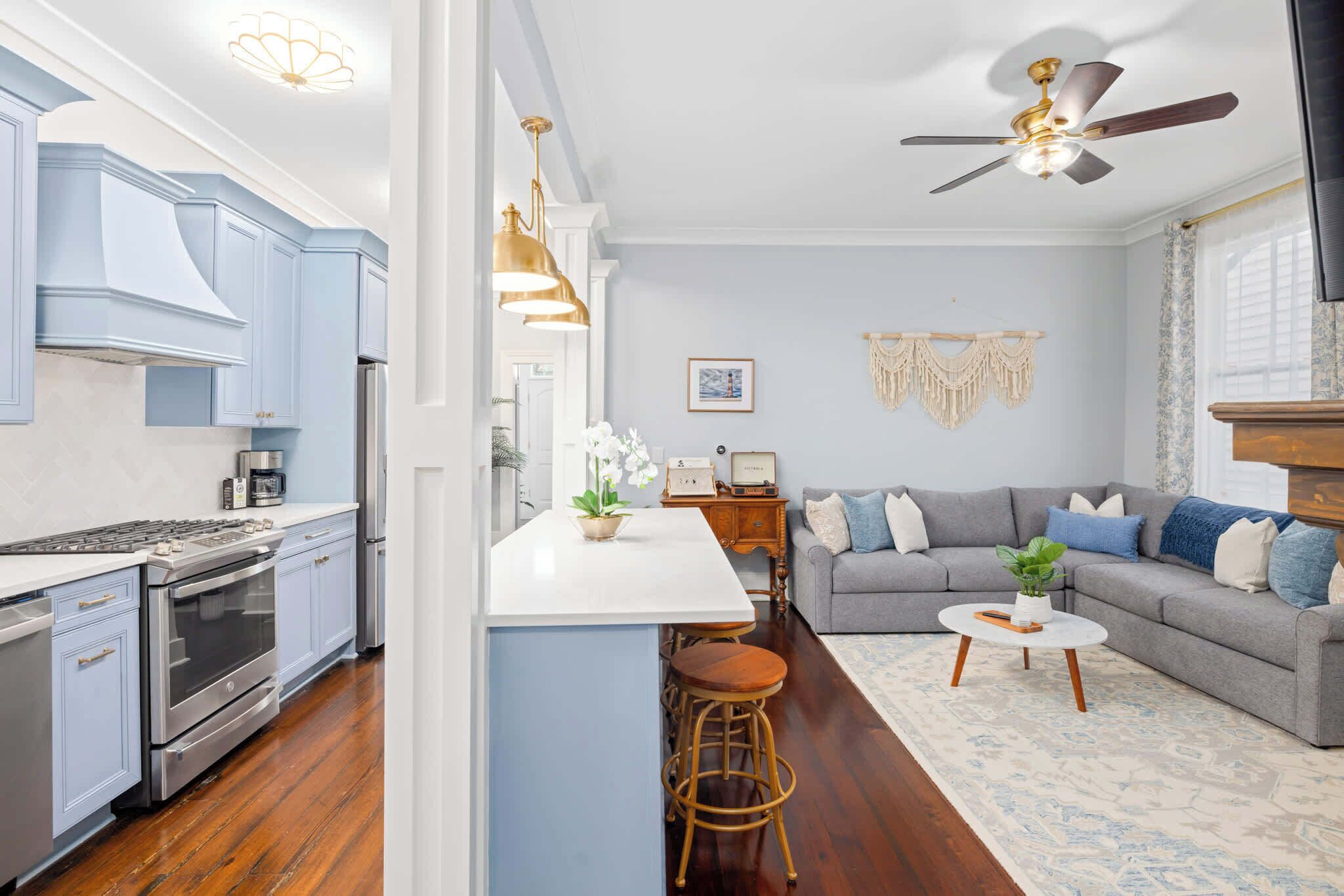 A modern kitchen with a central island, a grey sofa, and a ceiling fan.