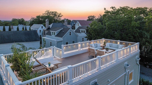 A residential deck with a white railing, surrounded by trees and houses. - Rooftop • Hot Tub • Parking • Walk to King St! (Charleston)