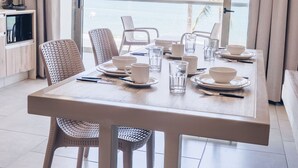 A dining area with a table set for two, a TV, and a view of the ocean. - Avenir Armonia Suites (Rincón de Guayabitos)
