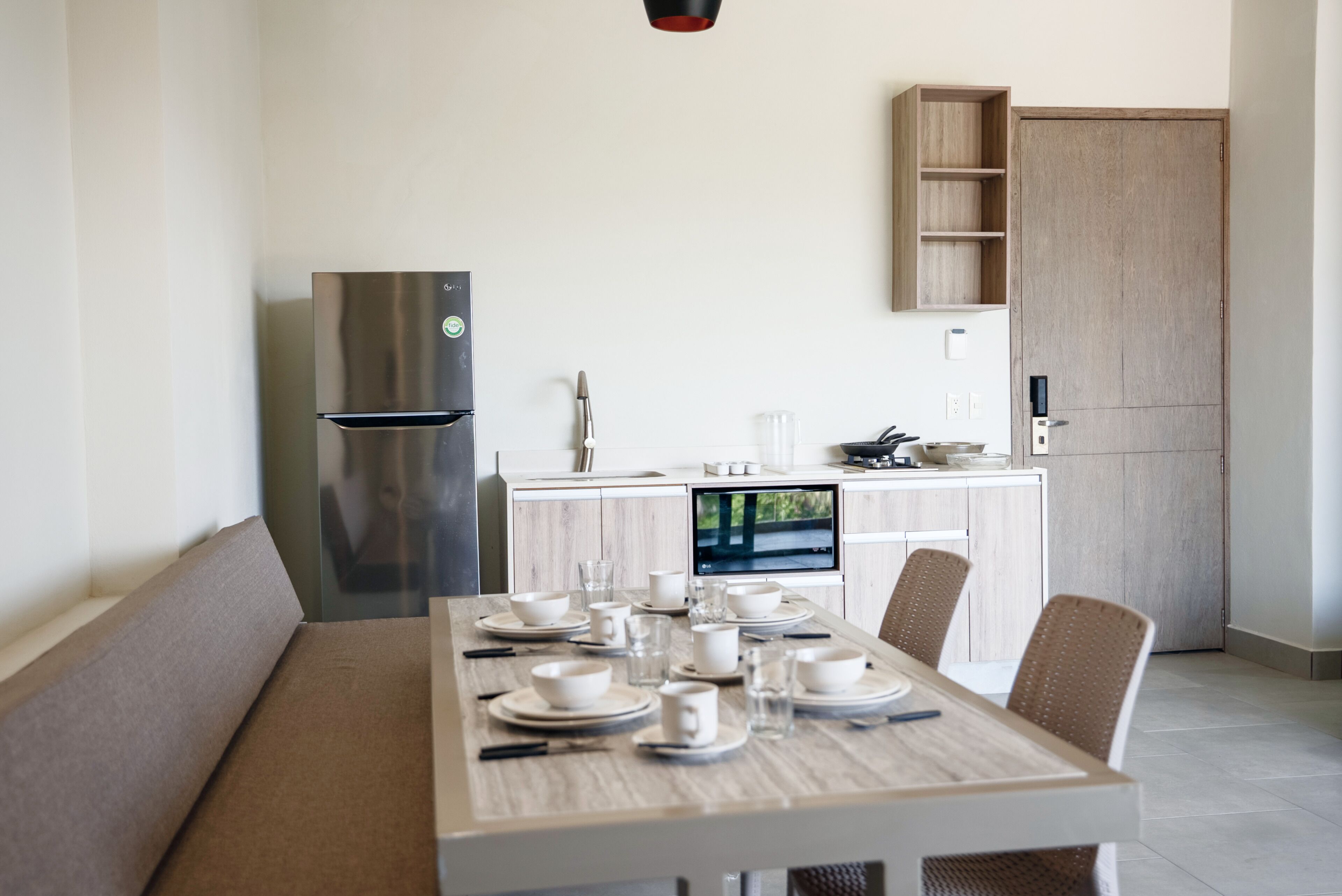 A modern kitchen with a built-in microwave, a stainless steel refrigerator, and a dining area with a table set for four.