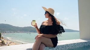 A person sitting by a pool with a view of a beach and the sea. - Avenir Armonia Suites (Rincón de Guayabitos)