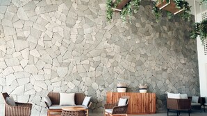 A stone wall with wicker furniture and a wooden table. - Avenir Armonia Suites (Rincón de Guayabitos)