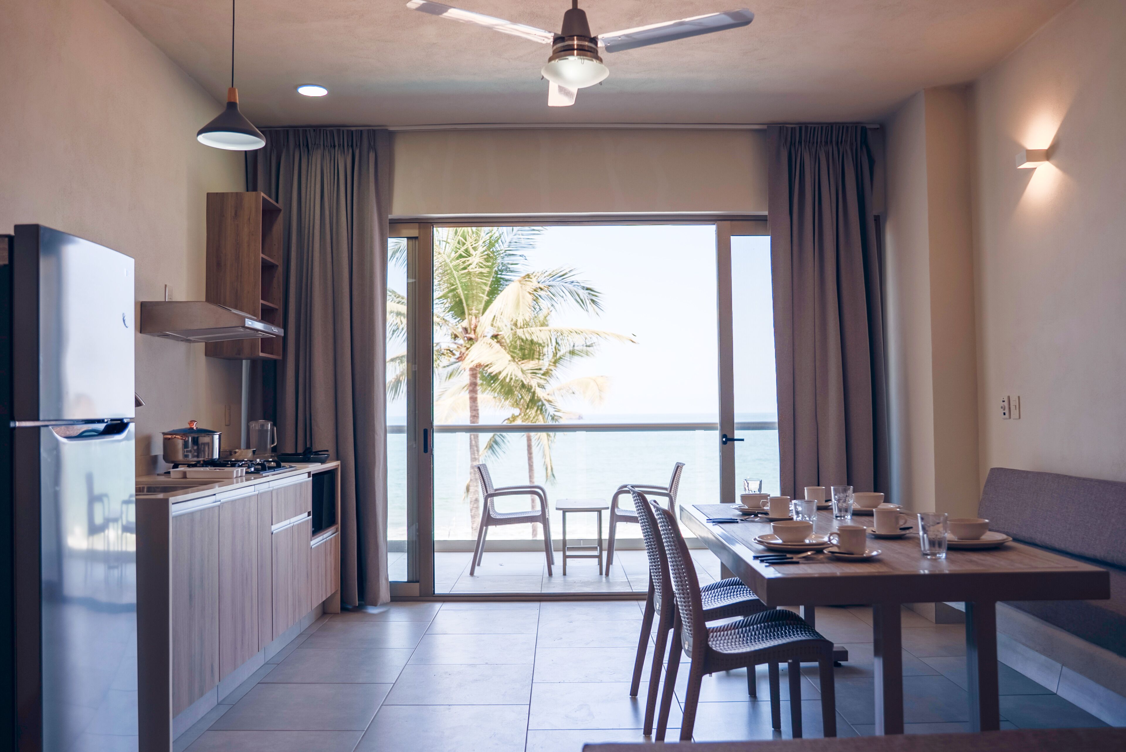 A modern kitchen with a dining area, large windows, and a view of the ocean.