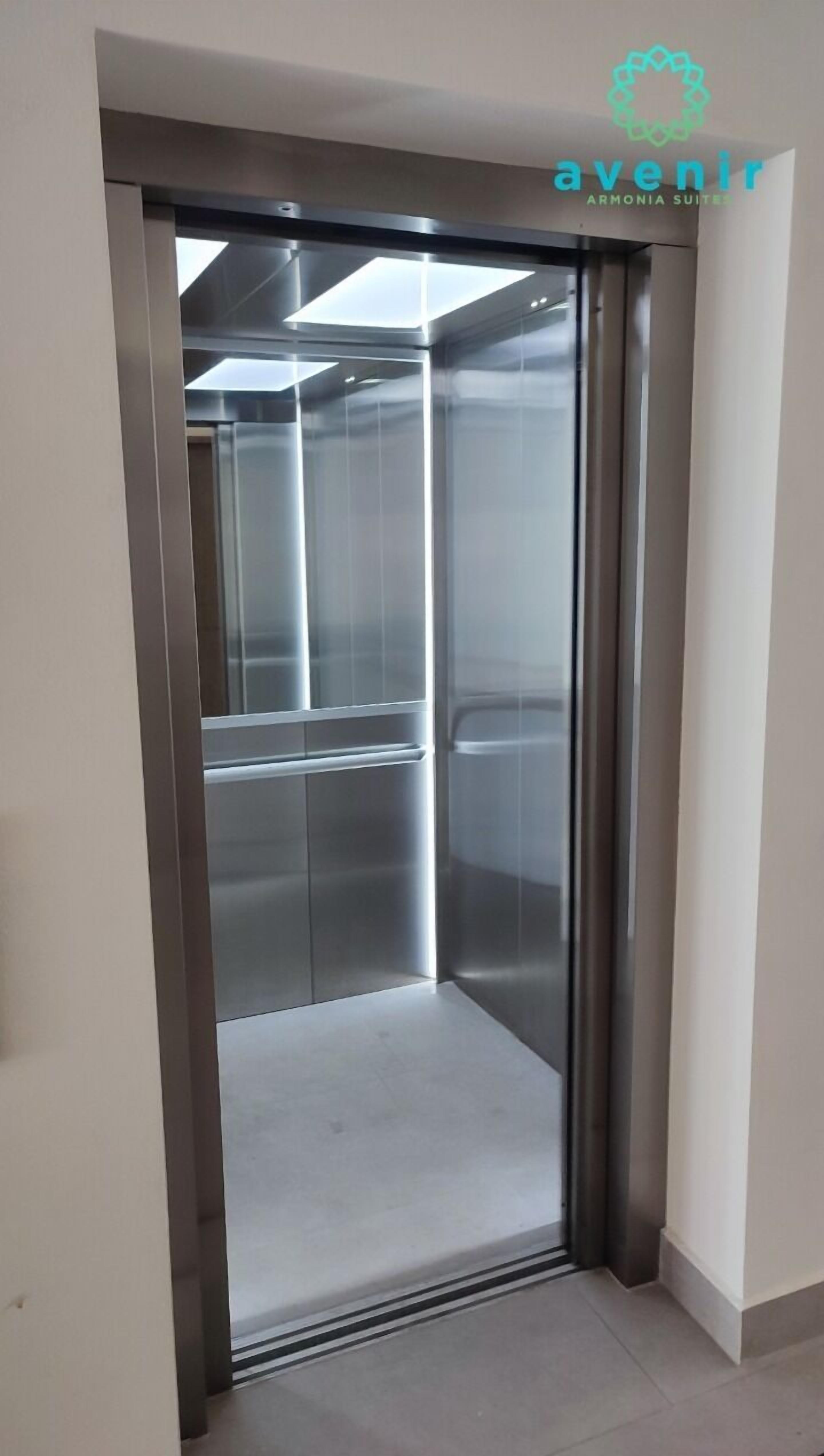 A modern elevator with metallic walls and a glass door, part of a building with a minimalist design.