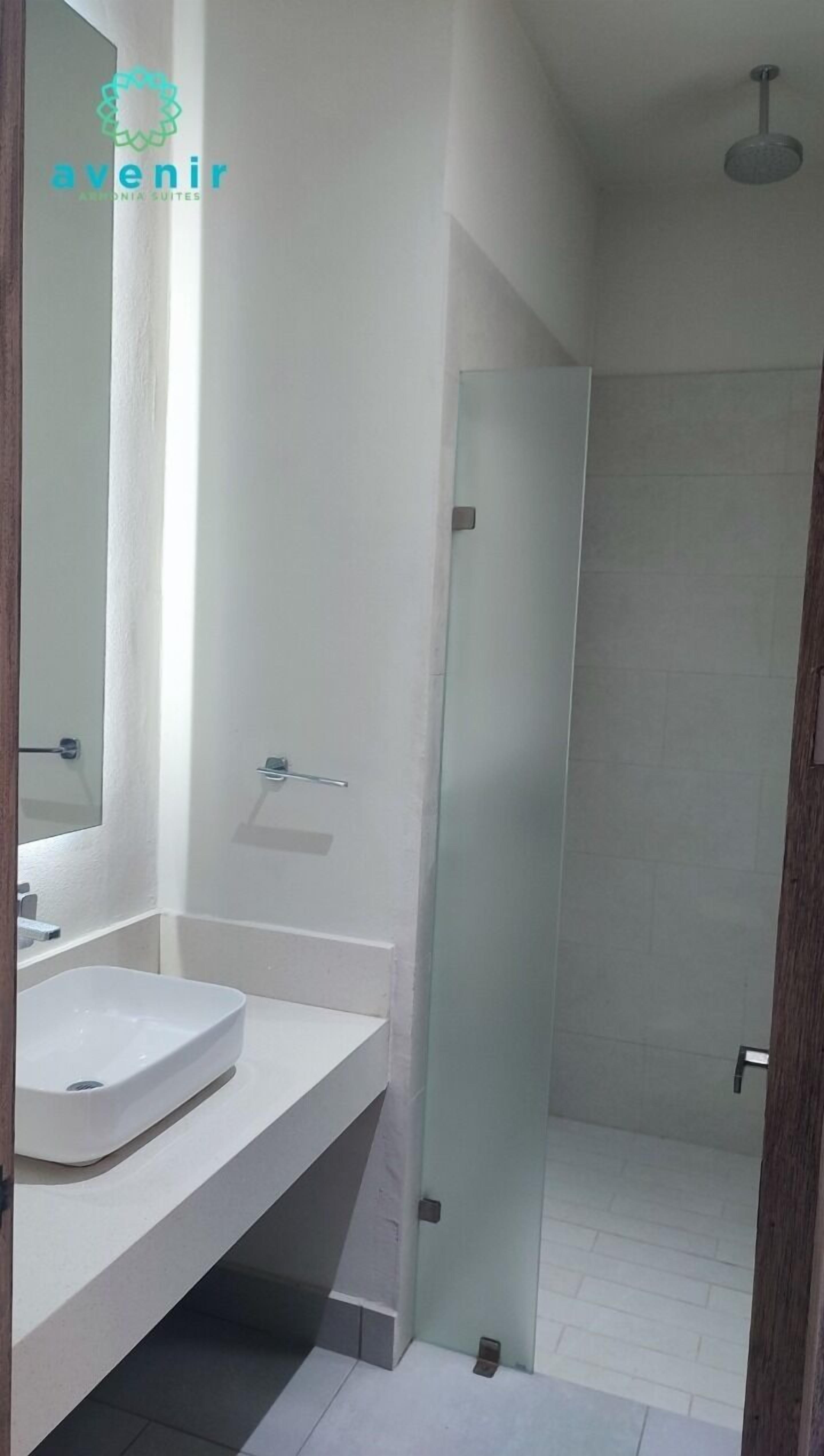 A bathroom with a white sink, mirror, and glass shower enclosure.
