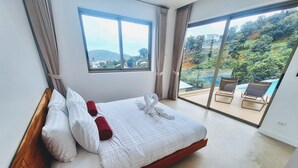A hotel room with a large bed, a view of a swimming pool, and a balcony with chairs.