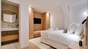 A modern bedroom with a large bed, a built-in TV, a wooden wardrobe, and a bathroom with a mirror and sink. - Sumptuous Apartment - 2br/6p - Center of Paris (Paris)