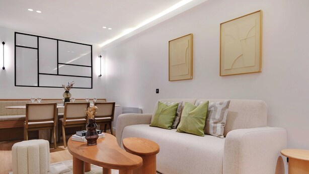 A modern living room with a sofa, wooden coffee table, and ottoman. There is a dining area with chairs and a vase of flowers. - Sumptuous Apartment - 2br/6p - Center of Paris (Paris)