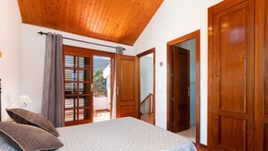 Une chambre à coucher avec un lit, une armoire en bois et un balcon où sont posés des livres.