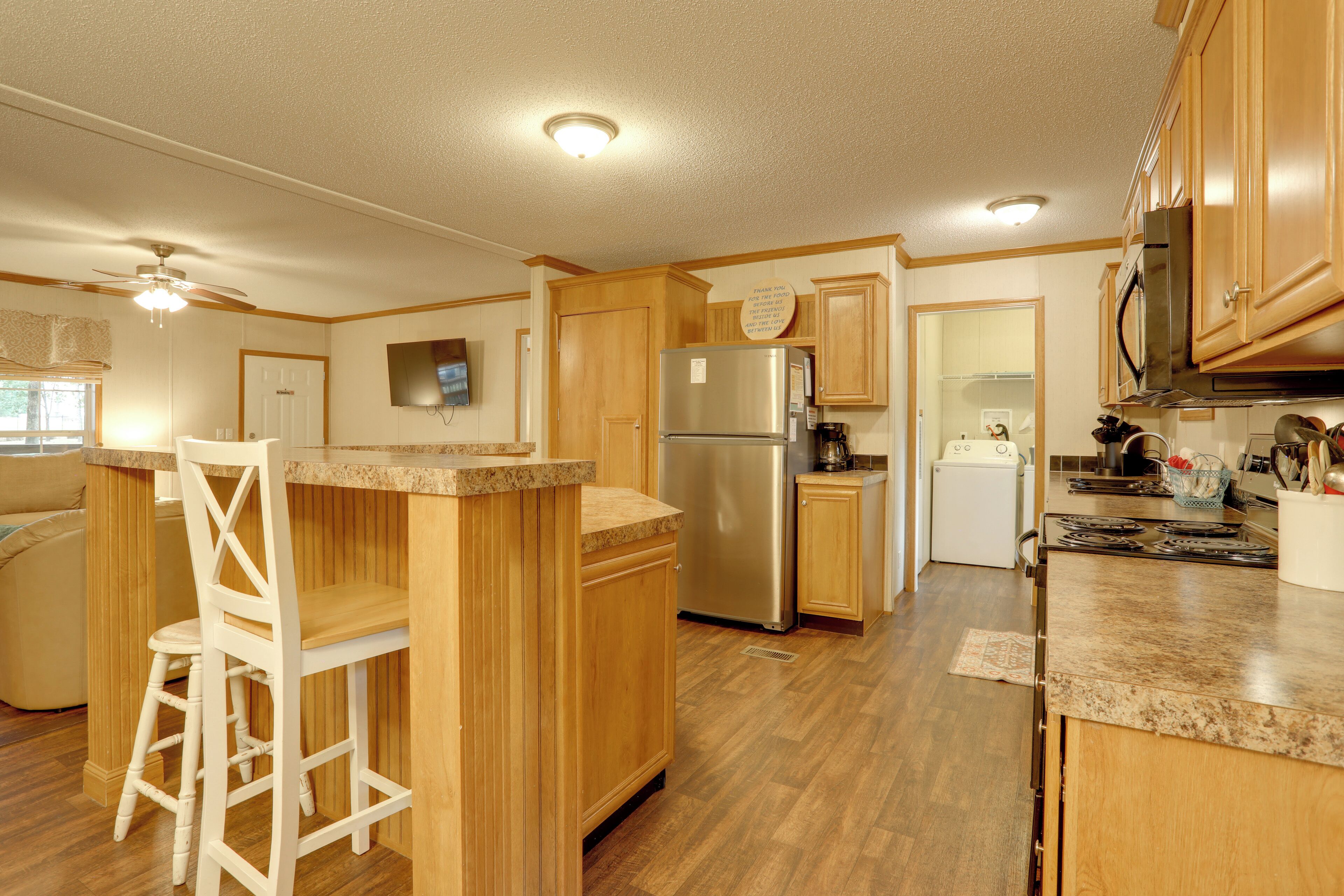 A kitchen with wooden cabinets, a stainless steel refrigerator, a microwave, and a stove.