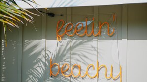 Una pared con las palabras "feelin' beachy" en luces de neón anaranjadas.