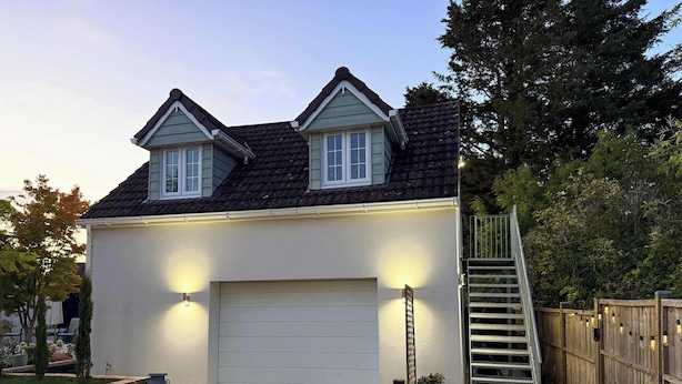 A two-story house with a white garage door, a small front porch, and a wooden fence. - The Frog, Langport Luxury (Huish Episcopi)