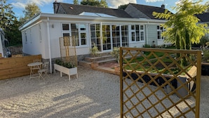 A white house with a conservatory, gravel driveway, and a wooden fence. - The Frog, Langport Luxury (Huish Episcopi)