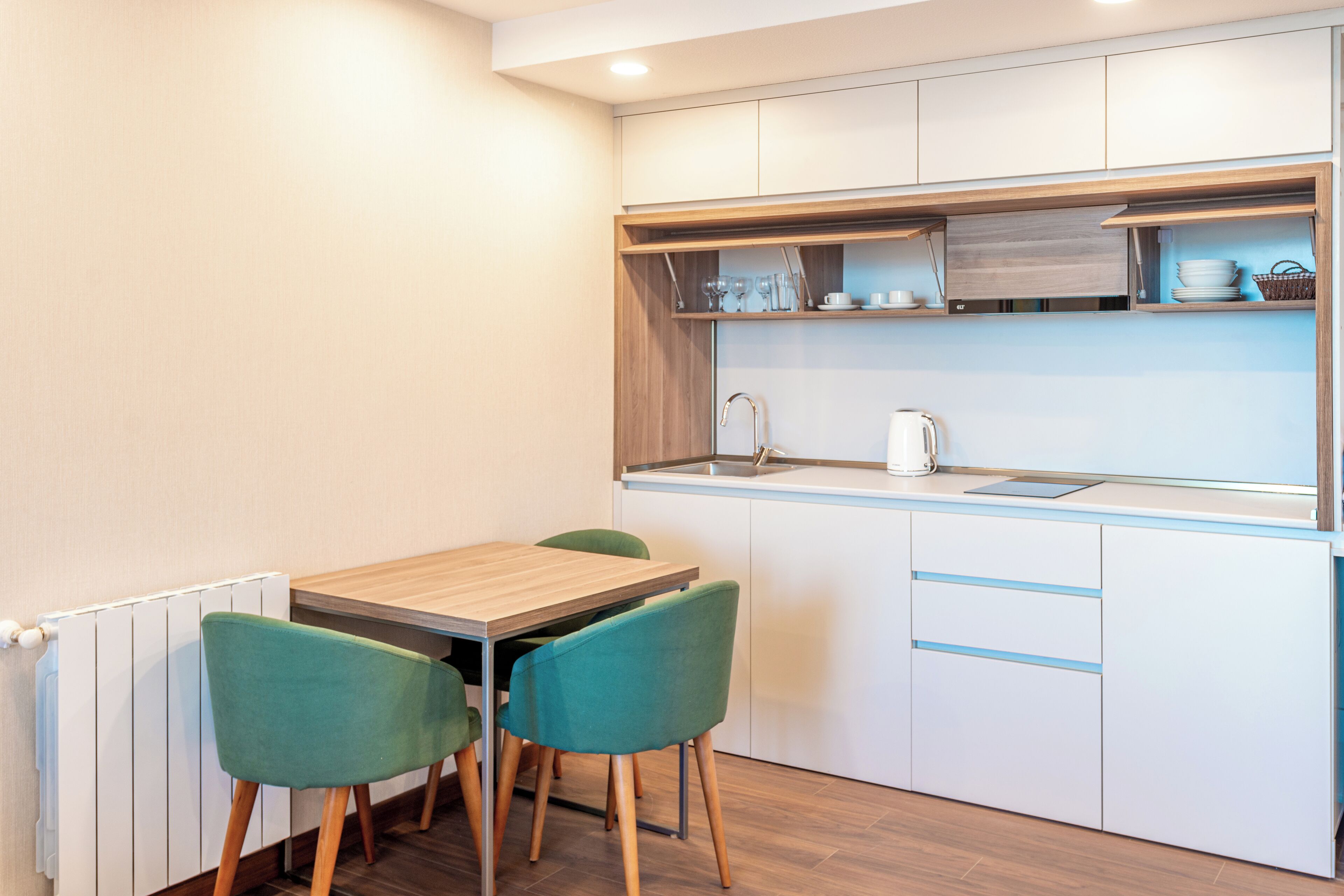A compact kitchen with a wooden table and two chairs, a sink, and cabinets above the counter.