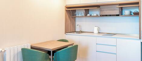 A compact kitchen with a wooden table and two chairs, a sink, and cabinets above the counter.