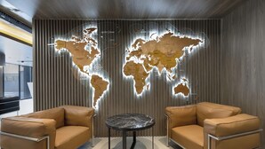 A modern interior with two brown leather sofas, a round black table, and a world map mural on the wall. - Sunset Residence & Hotel Batumi (Batumi)