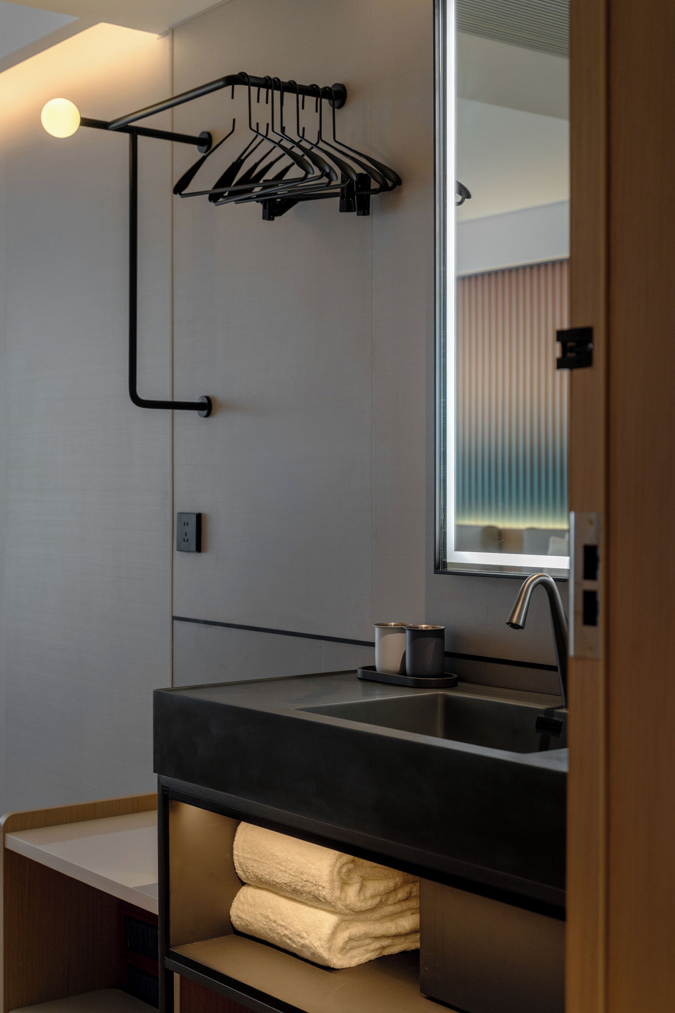 A modern bathroom with a black sink, towel rack, and a mirror.