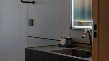 A modern bathroom with a black sink, towel rack, and a mirror.