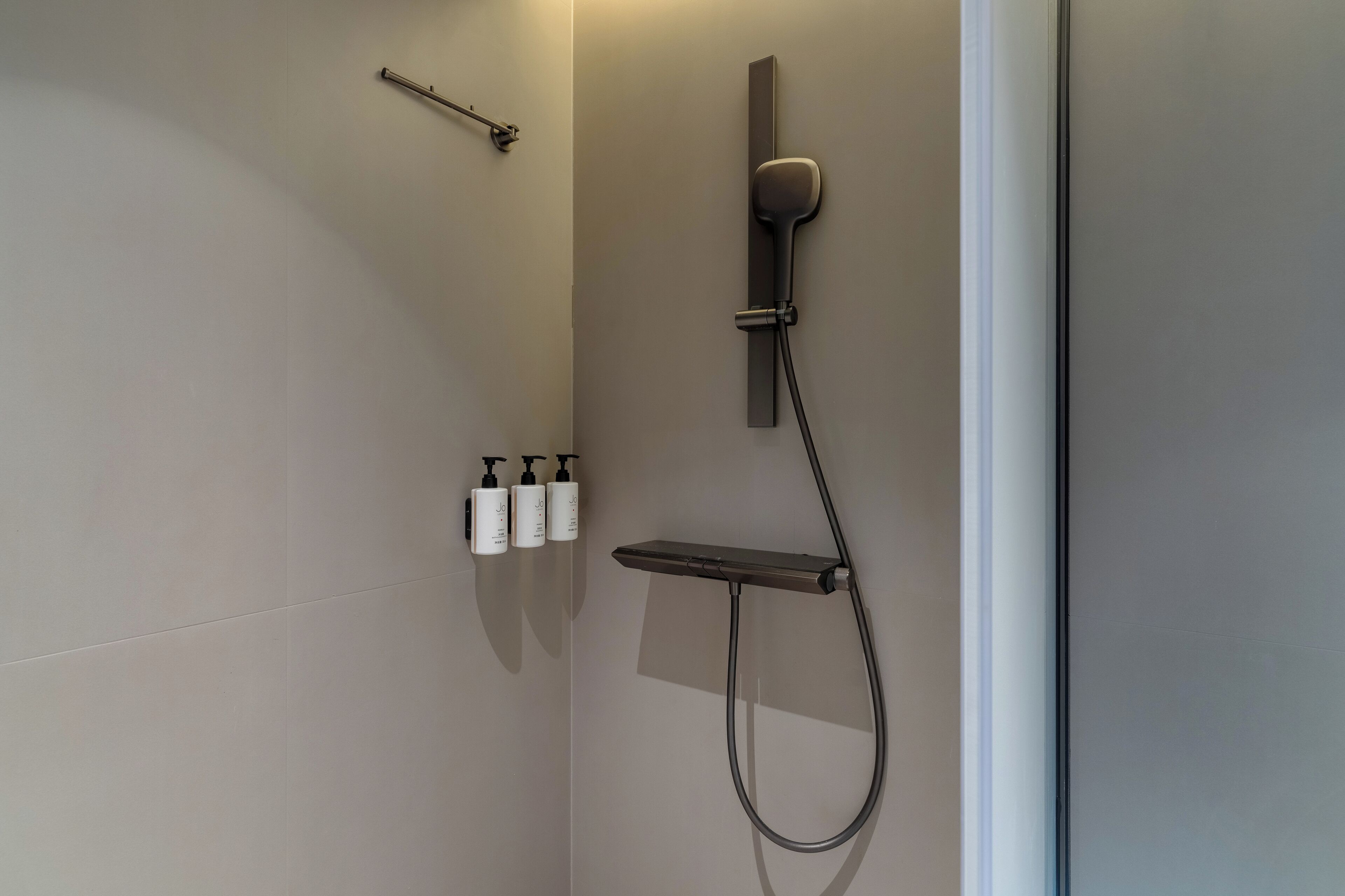 Ducha moderna con cabezal de ducha de mano y panel de control en la pared.