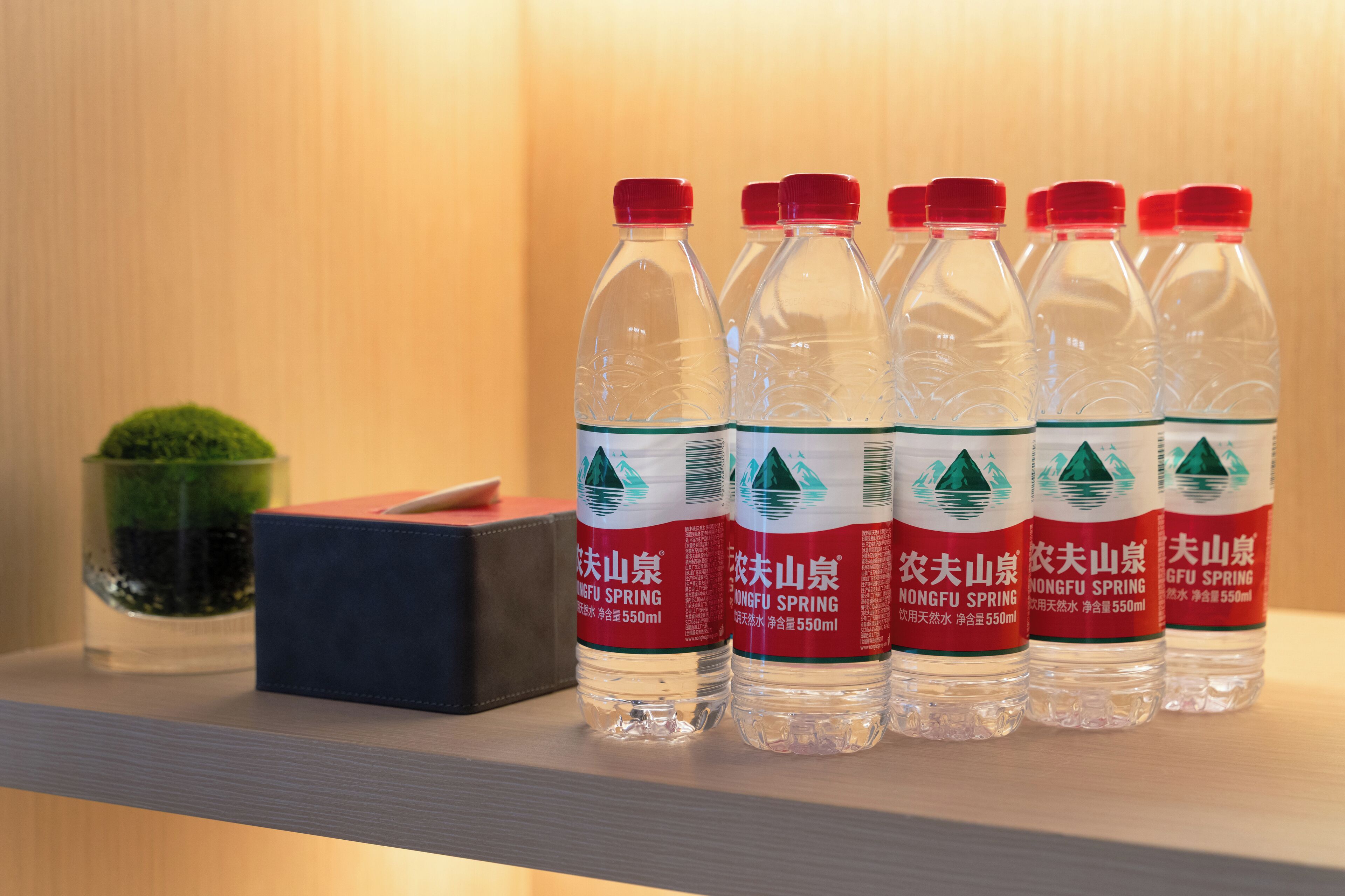 Six bouteilles d’eau Nongfu Spring sont posées sur une étagère.