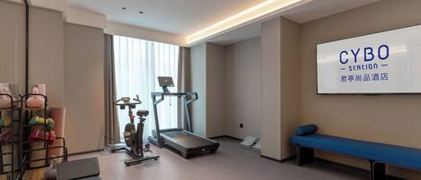Une chambre d’hôtel moderne équipée d’un tapis de course, d’appareils de musculation et d’une grande enseigne « CYBO Station ».