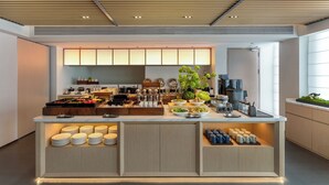 Une cuisine moderne dotée d’un îlot central, équipée de divers appareils électroménagers, d’une machine à café et d’une variété de produits alimentaires.