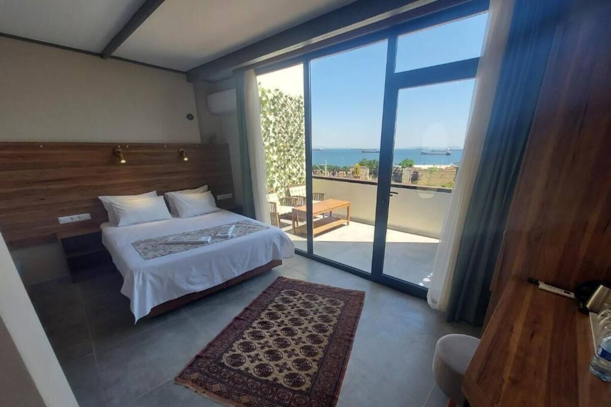 A bedroom with a bed, a rug, a desk, and a balcony with a view.
