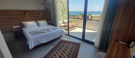 A bedroom with a bed, a rug, a desk, and a balcony with a view.