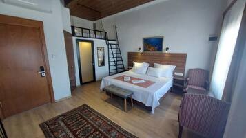 Quarto com cama, um banquinho, uma cadeira, uma escada e um quadro na parede.