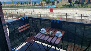 A balcony with a table set for two, overlooking a coastal area with a playground and a building in the background. - Queen Seagull Boutique Hotel (İstanbul)