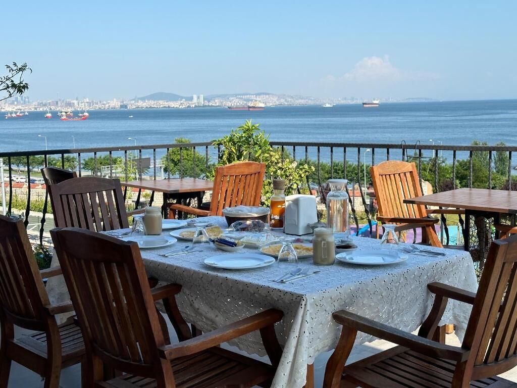 A table set for dining with a view of the sea and city skyline.