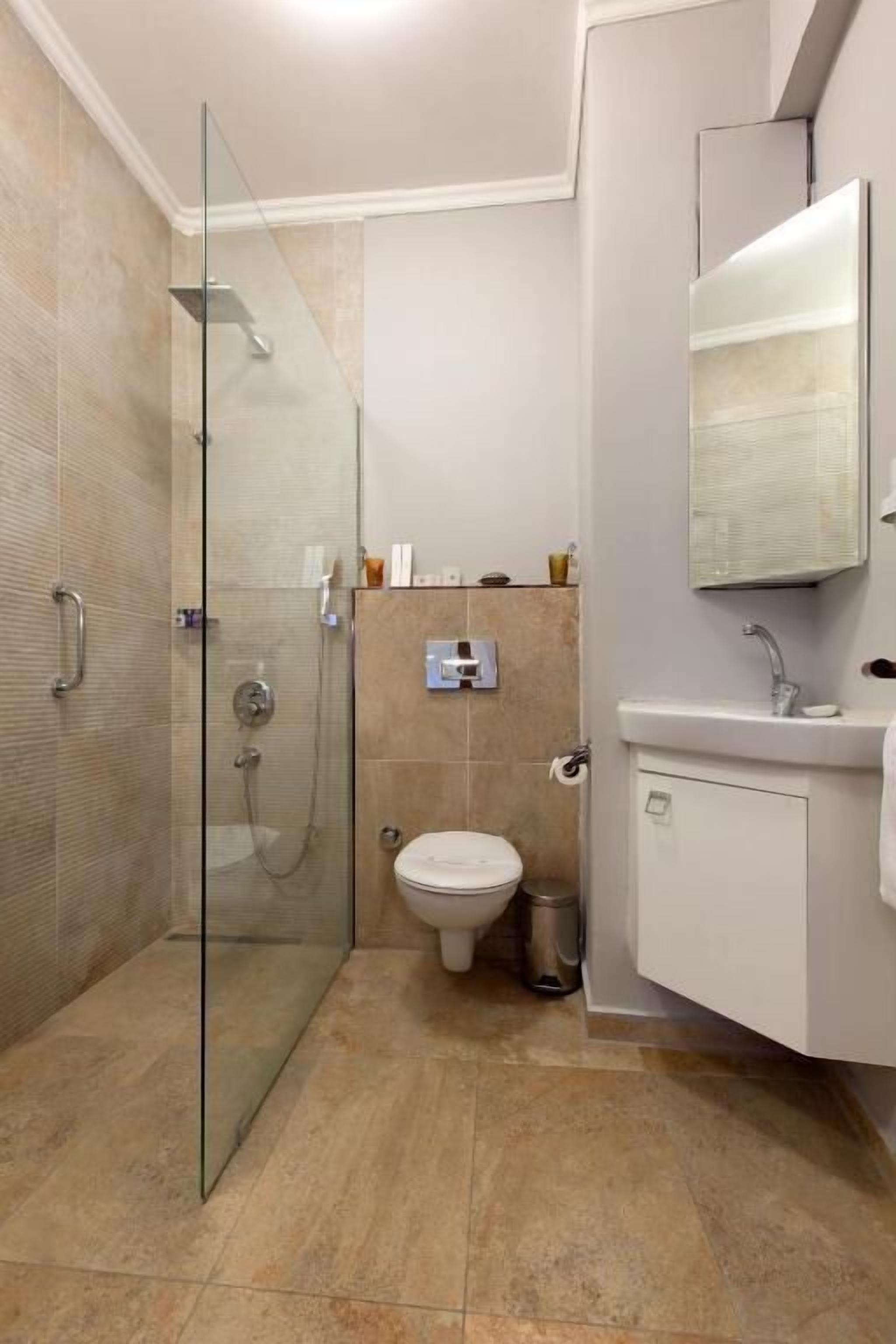 A modern bathroom with a glass-enclosed shower, a toilet, a sink, and a mirror.