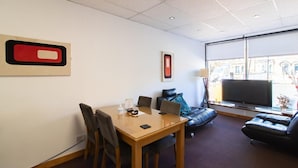 Una sala de conferencias con una mesa de madera, sillas, un sofá y un televisor.
