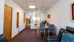 Une chambre d’hôtel compacte comprenant un coin cuisine, un espace repas et un coin salon avec un canapé et des fauteuils.