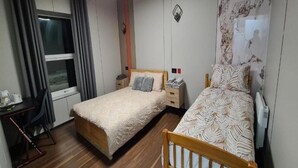 A bedroom with two beds, a desk, and a chair.