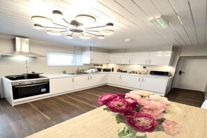 A modern kitchen with white cabinets, a black stove, and a wooden countertop. - OYO Welsh Accomodation Standard Family of 3 Room (Pembroke Dock)
