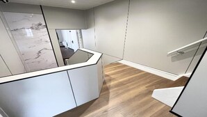 A modern interior with a wooden floor, a white staircase, and a marble wall.