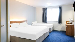 A hotel room with two beds, a small desk, a window with curtains, and a blue carpet. - Standard Family of 3 Room (Lancaster)