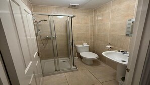 A bathroom with a glass shower enclosure, a toilet, and a sink.