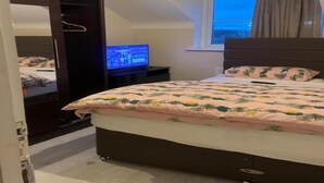 A bedroom with a bed, a TV, a window, and a wardrobe. - Standard Double Room (Manchester)
