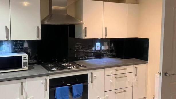 A modern kitchen with stainless steel appliances, white cabinetry, and a black backsplash. - Standard Double Room (Manchester)