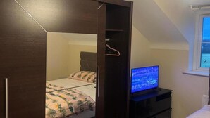 A bedroom with a bed, a TV, and a window. - Standard Double King room (Manchester)