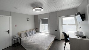 A modern hotel room with a bed, a desk, and a TV. - Standard Double Studio (Pembroke Dock)